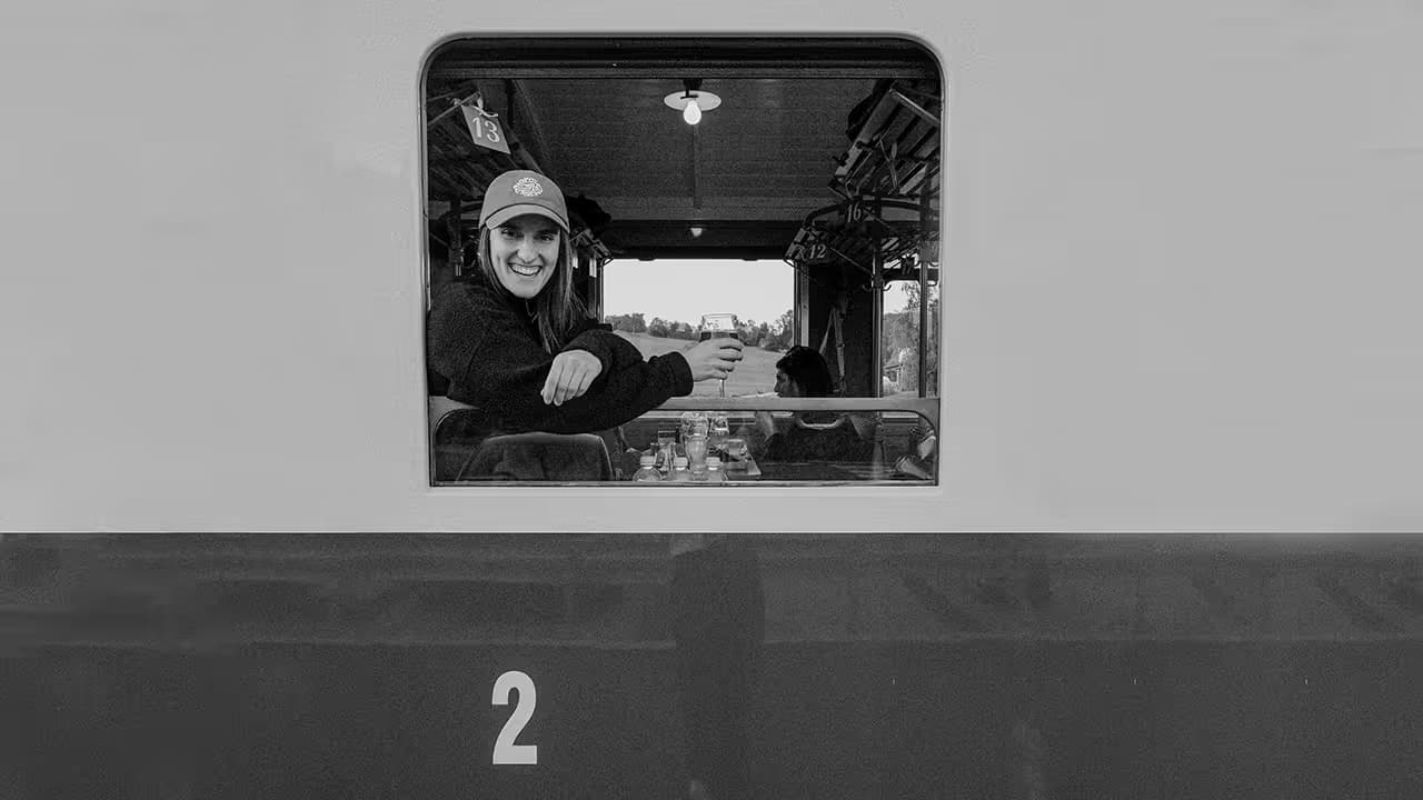 Black and white photo of Elisabeth Saehr smiling from the window of a vintage train carriage.